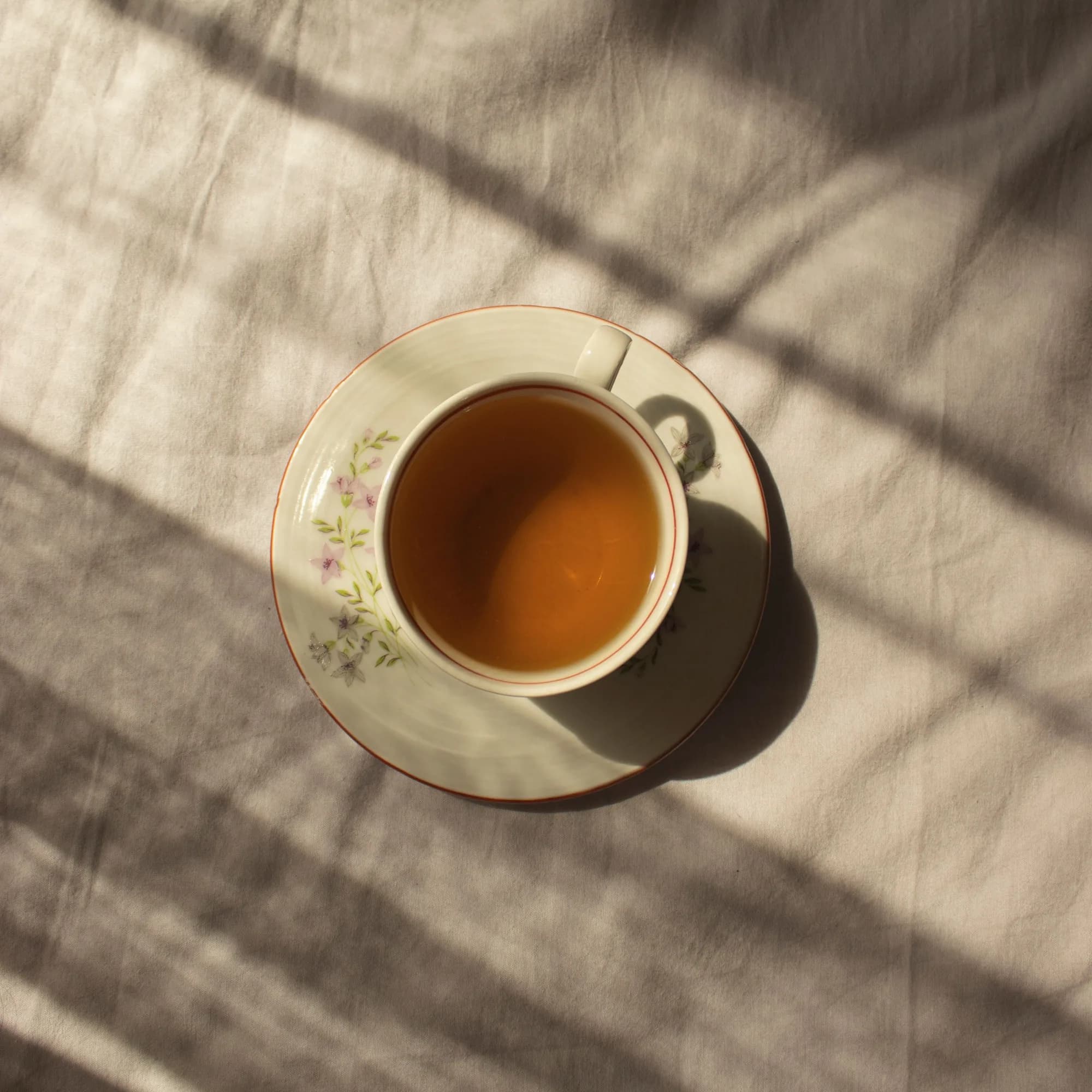 Eine Tasse Tee auf einem Leinentuch im Licht- und Schattenspiel